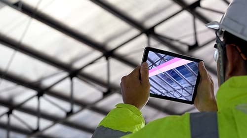 Man holding ipad looking up at building ceiling