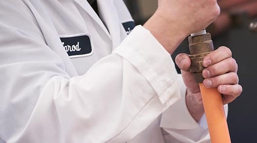 Person is while lab coat holding pipe