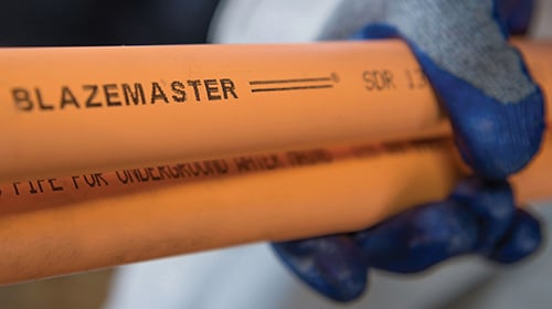 person with gloves holding multiple pieces of BlazeMaster CPVC piping
