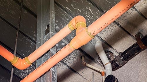 looking up at orange piping in ceiling