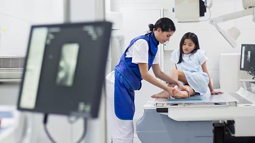 woman helping young girl on what looks like an x-ray table