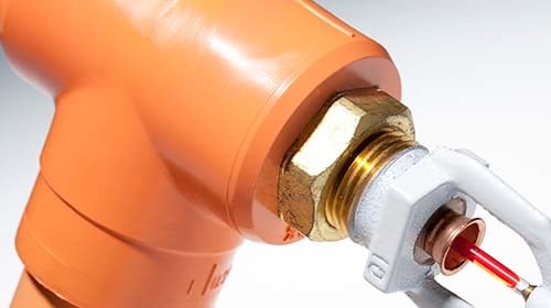 Close up view of orange sprinkler head and pipe