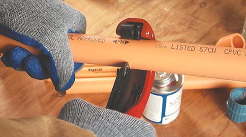 person about to cut a piece of orange pipe