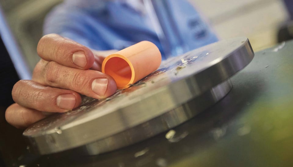 person holding orange CPVC piping on small round metal table