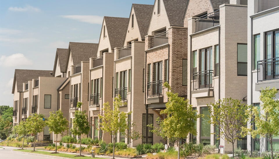 Row of homes on a sunny day with trees in front of each house